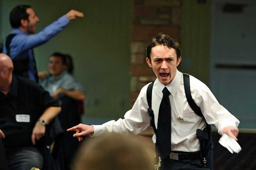 A person in a white shirt and black tie gesturing with one hand. 5