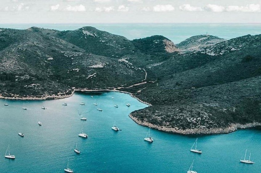A coastal landscape with boats anchored in a bay surrounded by hills. 2
