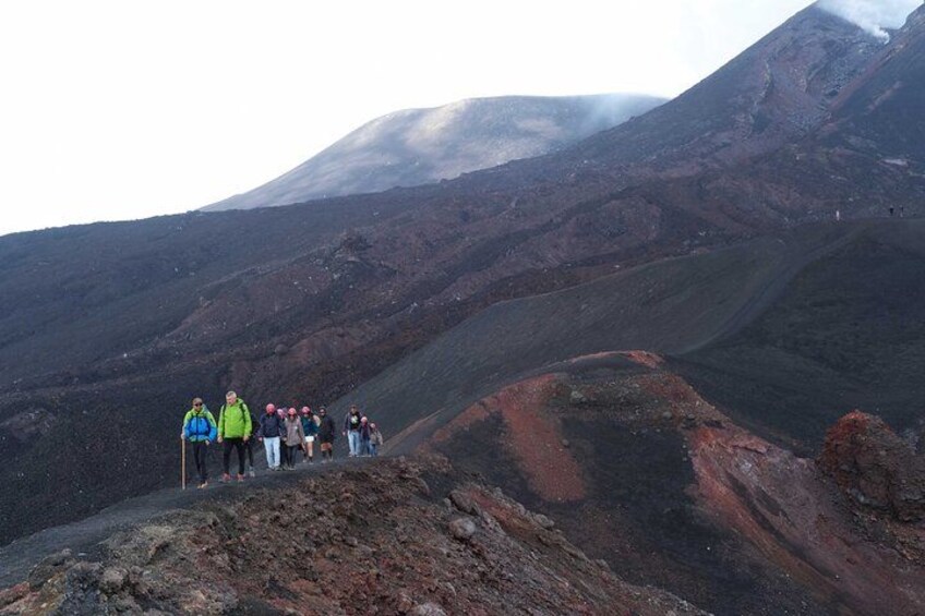 A group of hikers on a mountain trail with a volcano in the background. 4