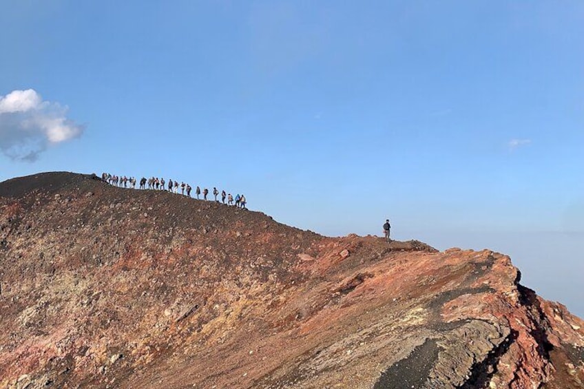 A group of people standing on a rocky hilltop with a clear sky. 5