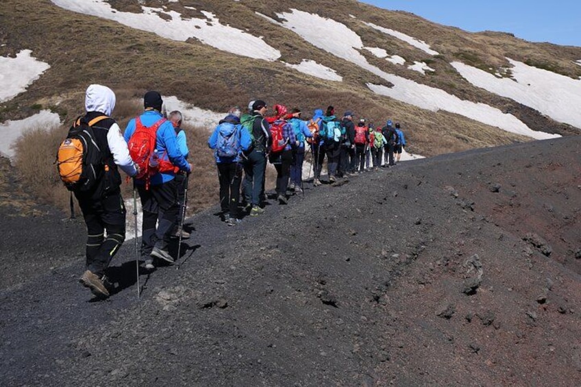Un grupo de excursionistas en un sendero rocoso con parches de nieve en la ladera. 5