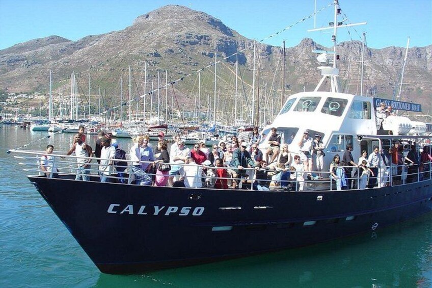 A boat named CALYPSO docked at a harbor with a mountainous backdrop. 5