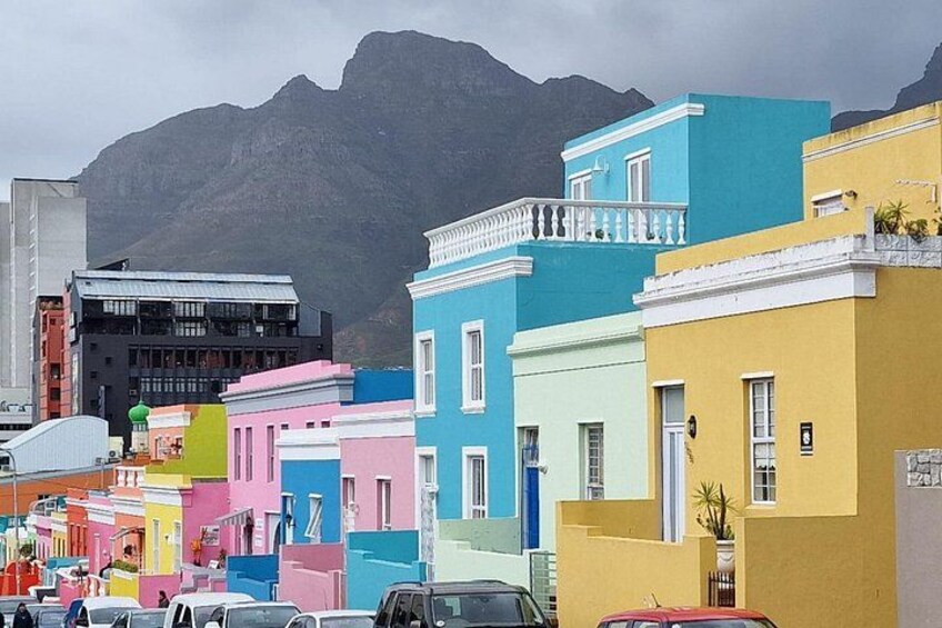 Colorful buildings, a mountain, and parked cars. 3