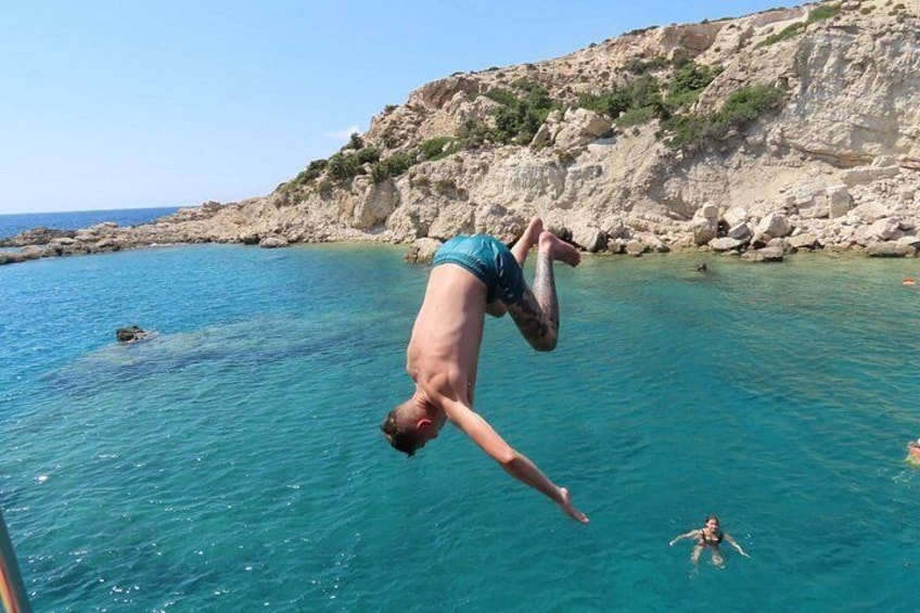 A person diving into clear blue water with rocky cliffs in the background. 4