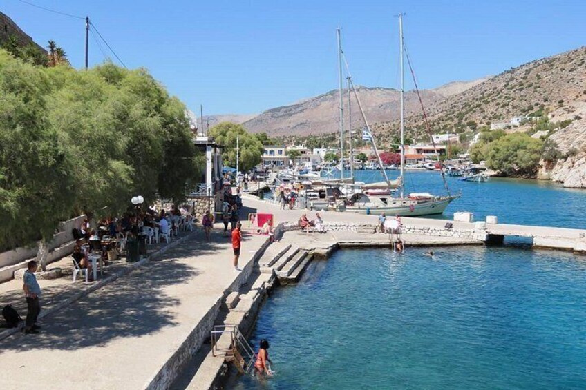 A coastal marina with boats, people, and a clear blue sky. 2