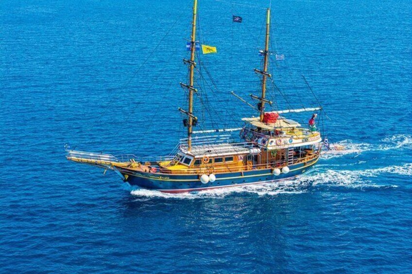 Un gran barco velero con varias mástiles y banderas navegando sobre un océano azul. 1