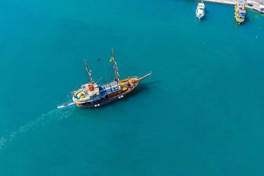A large, colorful ship anchored in clear blue water with smaller boats nearby. 4