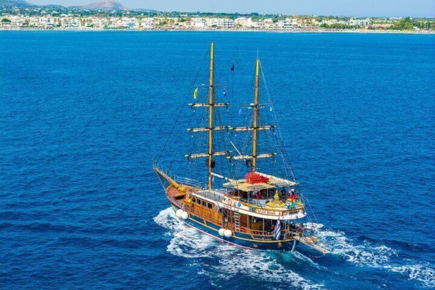 A tall ship sailing on a blue sea with a cityscape in the background. 3