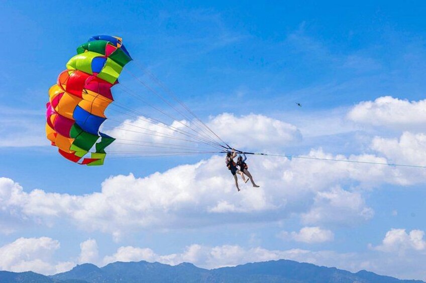 A person skydiving with a colorful parachute against a backdrop of mountains and clouds. 5