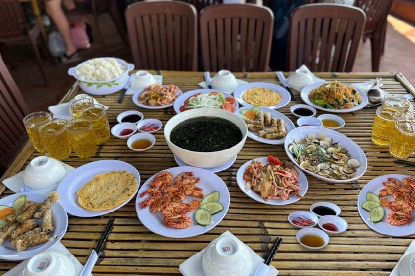 A wooden table with various dishes, drinks, and condiments. 3