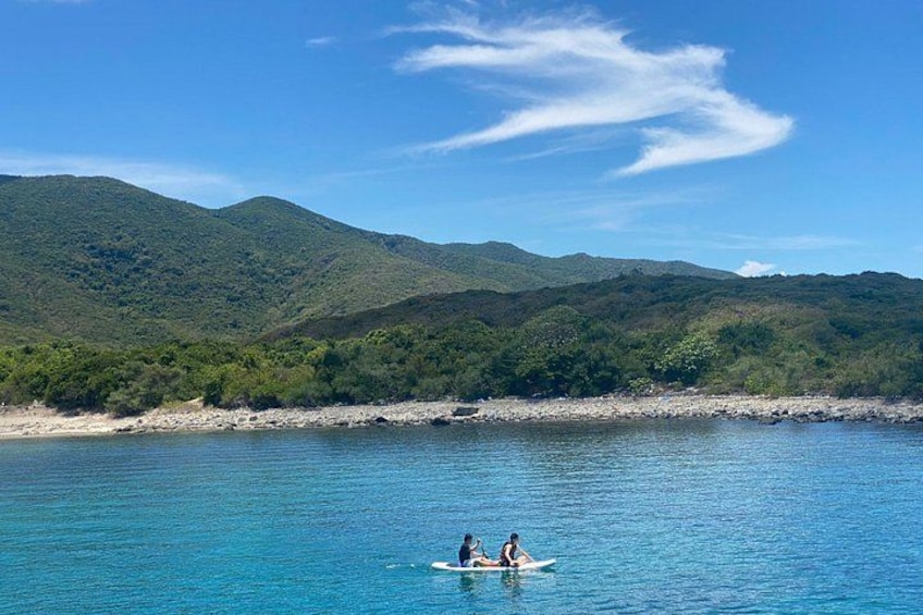 Un mar tranquilo con dos personas en un bote pequeño, rodeado de colinas verdes y exuberantes. 2