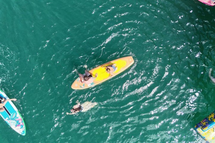 A person on a yellow paddleboard in the water, surrounded by other paddleboards. 4