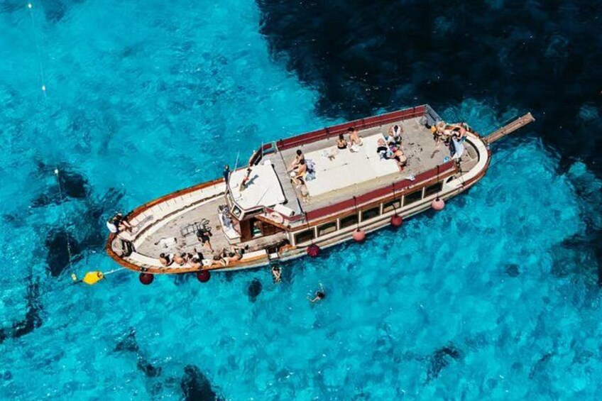 A boat with people on a clear blue sea. 2