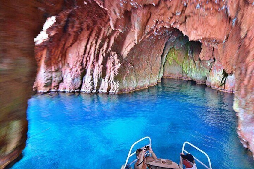 A boat in a cave with a clear blue pool. 2