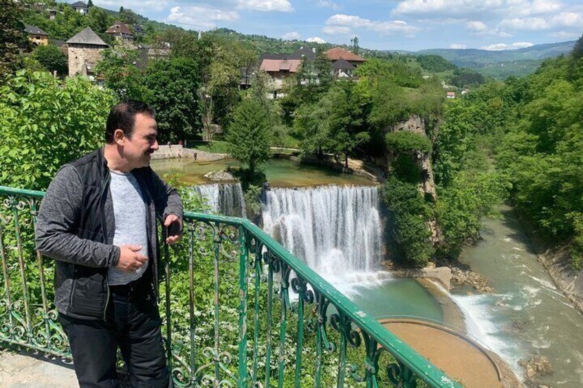 A person standing on a bridge overlooking a waterfall and a river. 1