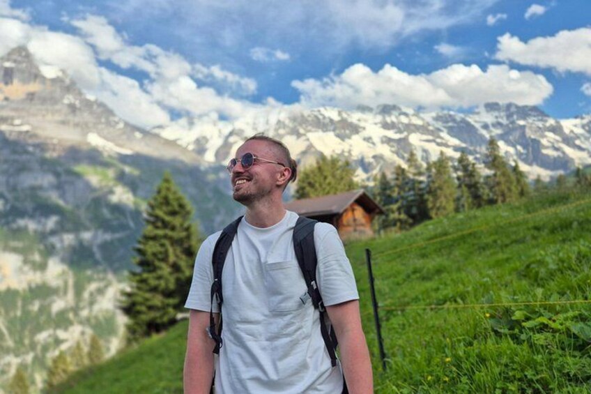 A person standing on a grassy hill with a mountainous landscape in the background. 3