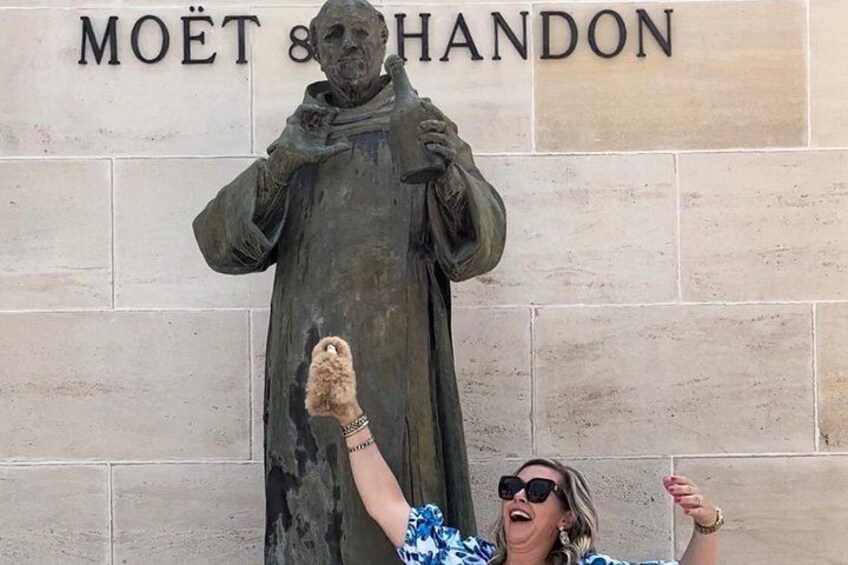 A statue of a robed figure with a raised hand, standing in front of a sign that reads 'MOËT & HANDON'. 4