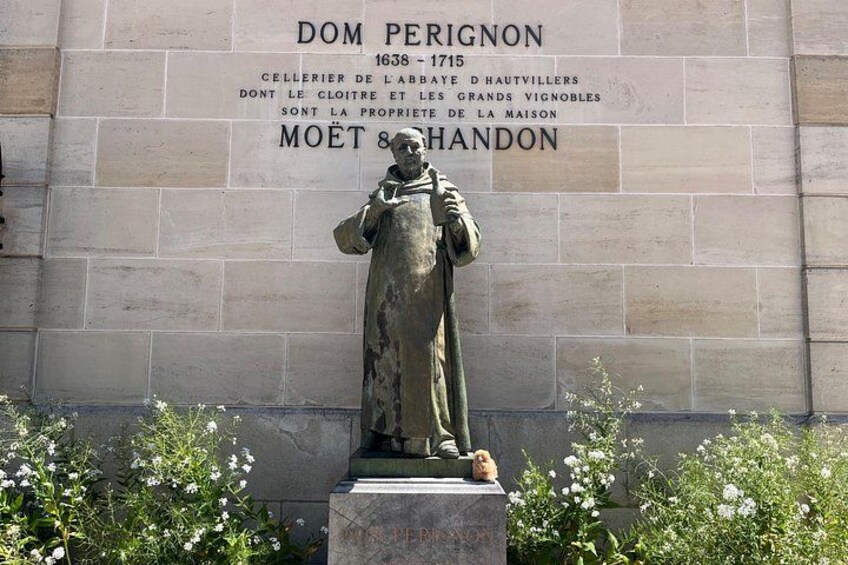 A statue of a man in a long robe, standing in front of a stone wall with inscriptions. 5