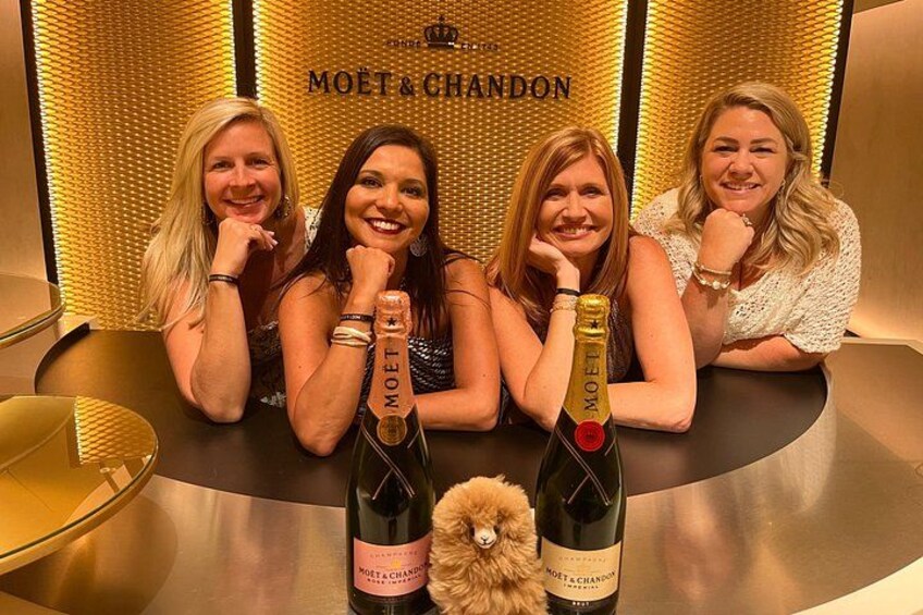 Four people sitting at a table with two bottles of Moët & Chandon champagne. 1