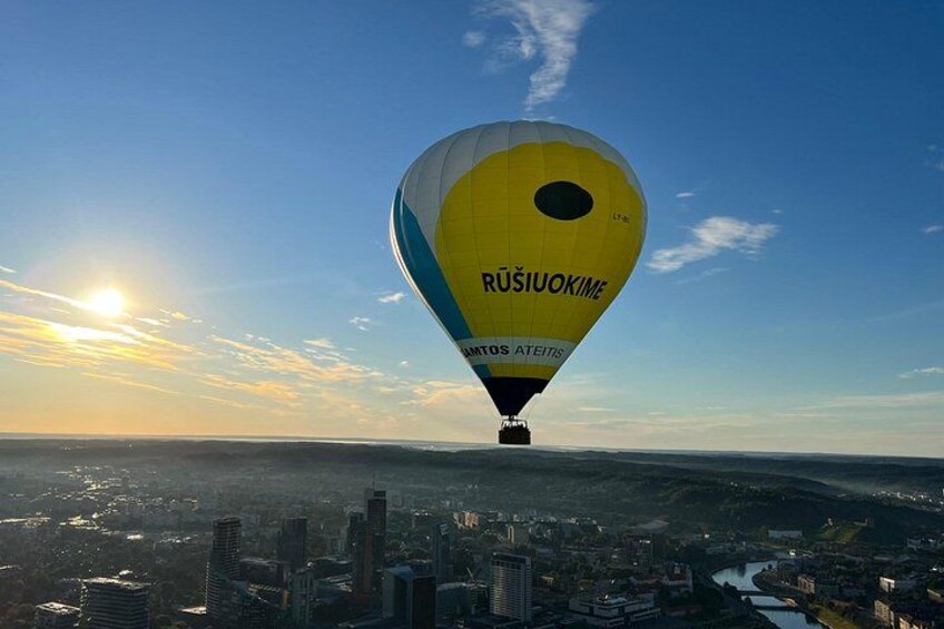 A hot air balloon with 'RUSIUKIMEN' written on it flying over a cityscape. 5