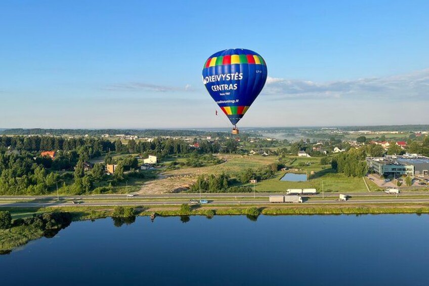 A hot air balloon over a body of water with a landscape in the background. 1