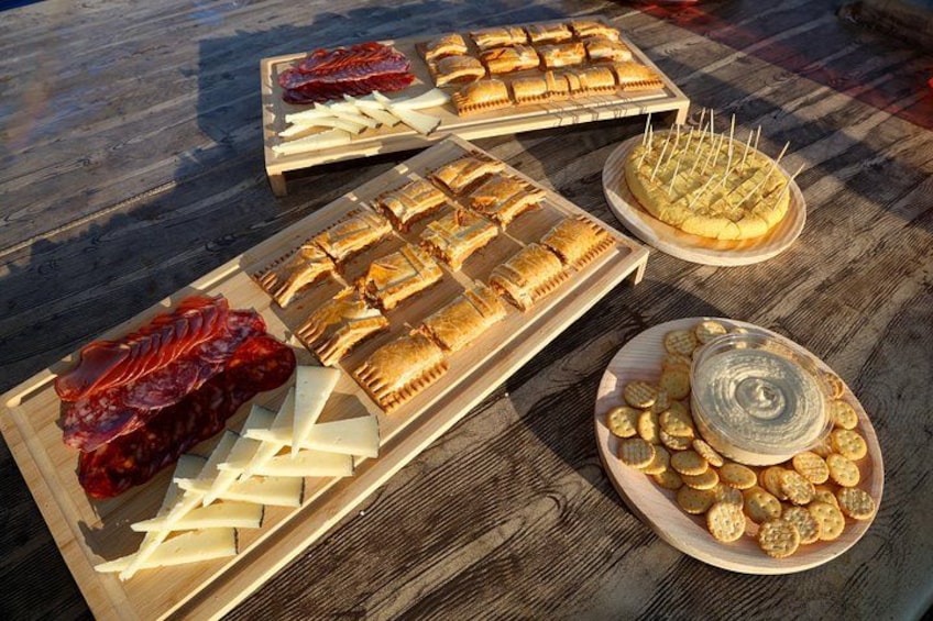 A wooden table with various food items including cured meats, cheeses, pastries, and crackers. 3