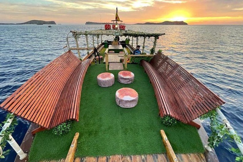 A boat deck with a wooden structure, green artificial grass, and round seating. 5