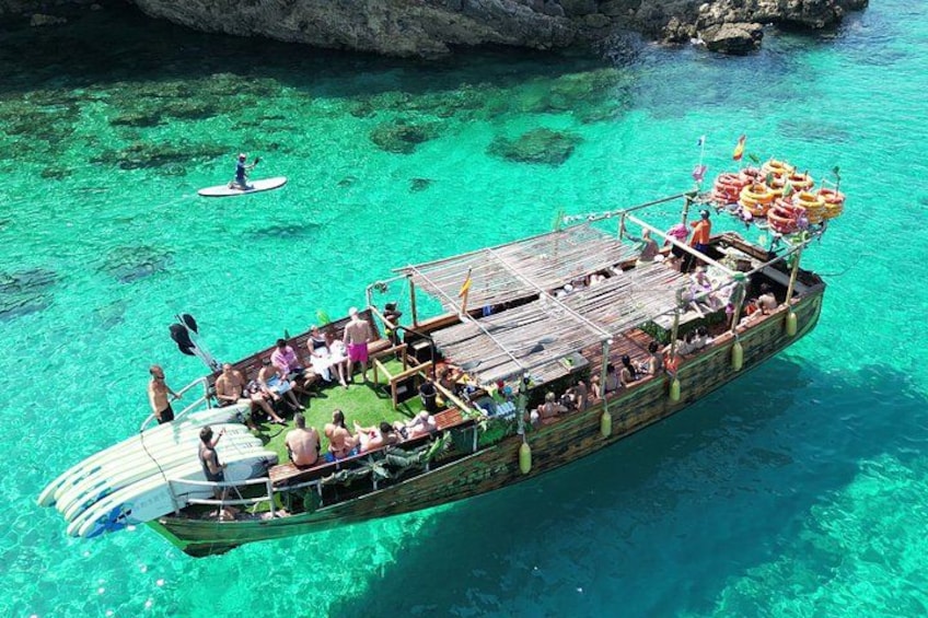 A boat with passengers and a paddleboarder in clear turquoise water. 2