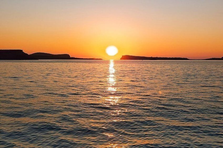 Een zonsondergang boven een rustige zee, met landsilhouetten in de verte. 3