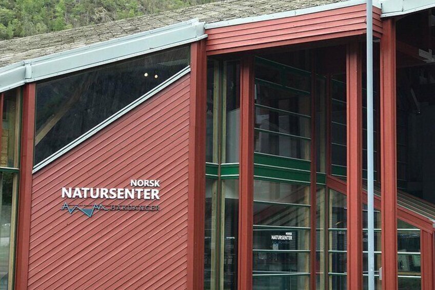 A building with a red facade and large windows, labeled 'Norsk Naturcenter.' 3