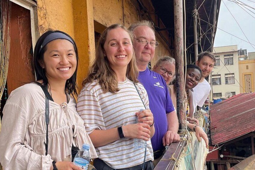 A group of people standing on a balcony with a building in the background. 2