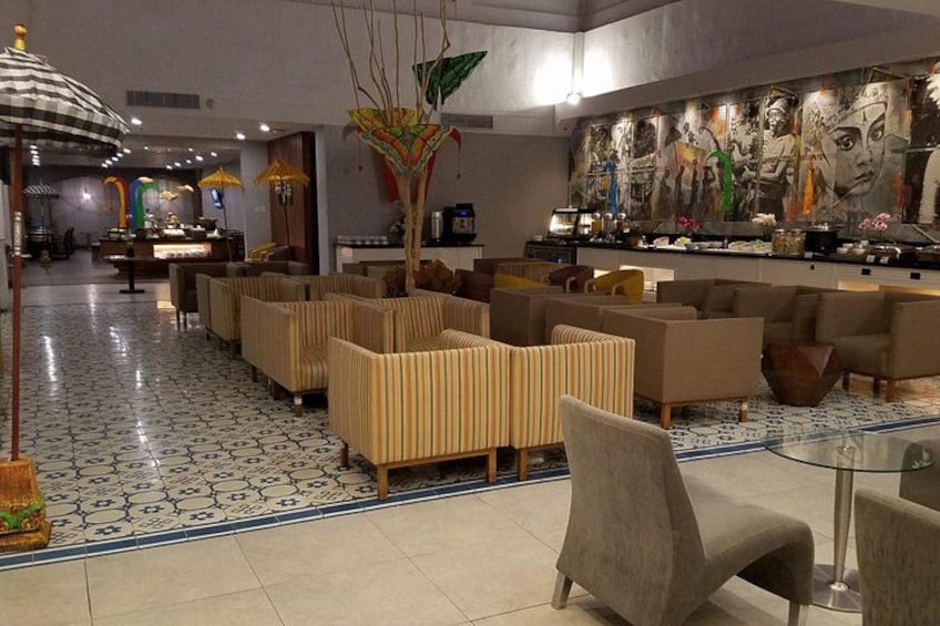 A modern lobby with seating areas, a reception desk, and a large mural. 2