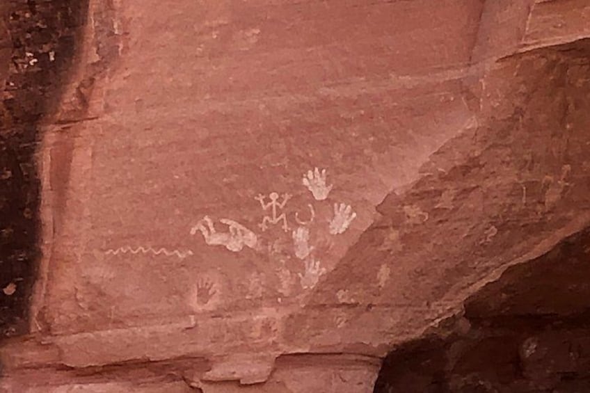 A rock surface with ancient petroglyphs including handprints and figures. 2
