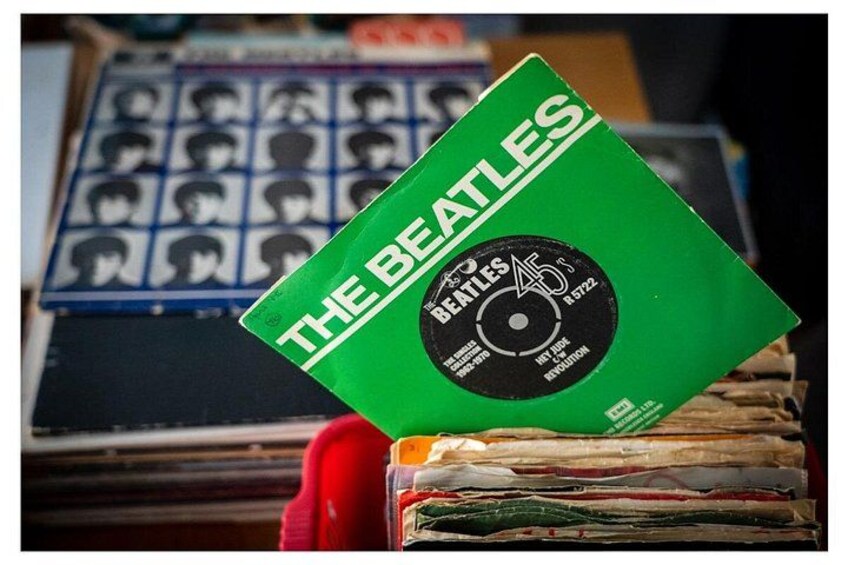 A green vinyl record of The Beatles with a black label, placed on top of a stack of records. 2