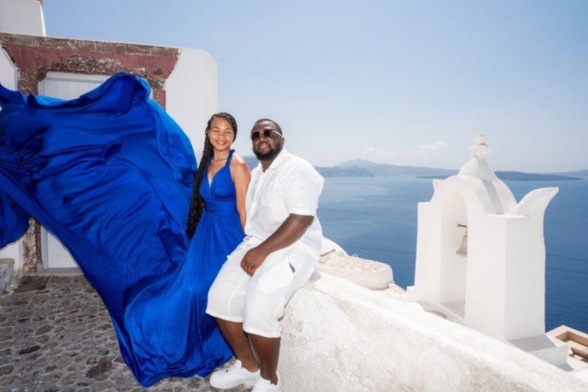 Una pareja frente a un edificio blanco; ella lleva un vestido azul y él, un atuendo blanco. 2
