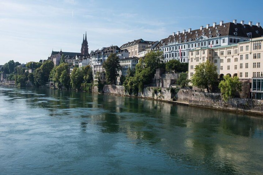 A river with buildings along the banks, a prominent church spire, and lush greenery. 3