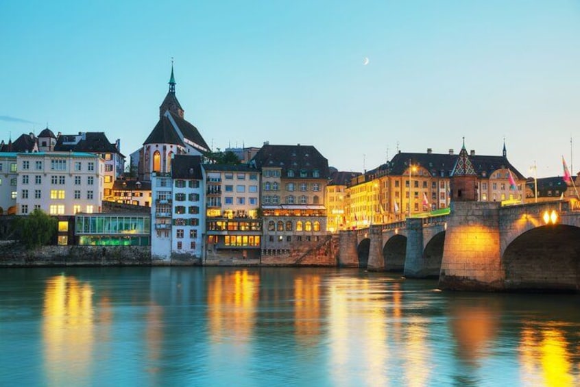 A historic bridge with multiple arches over a calm river, reflecting city buildings and a church steeple. 1