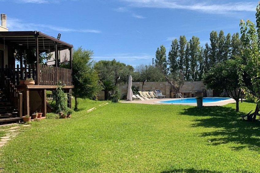 A backyard with a pool, a wooden deck, and a grassy lawn. 2
