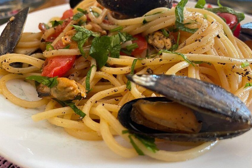 A plate of spaghetti with mussels, tomatoes, and herbs. 2
