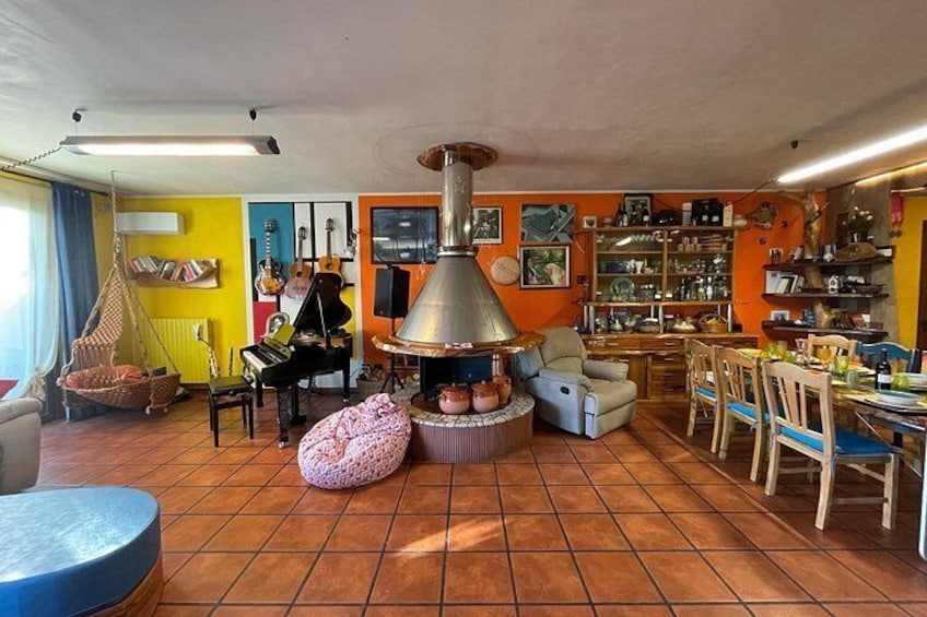 A cozy living room with a wood-burning stove, a hanging chair, a piano, and various decorative items. 3