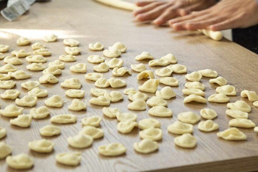 Una mesa de madera con masa moldeada en pequeñas piezas redondas, presumiblemente para cocinar. 4