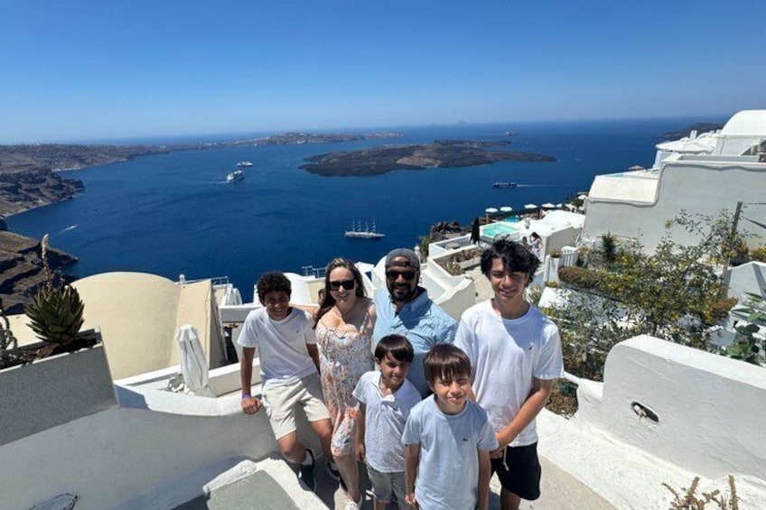 A group of people on a white-washed cliff overlooking a blue sea with boats. 4