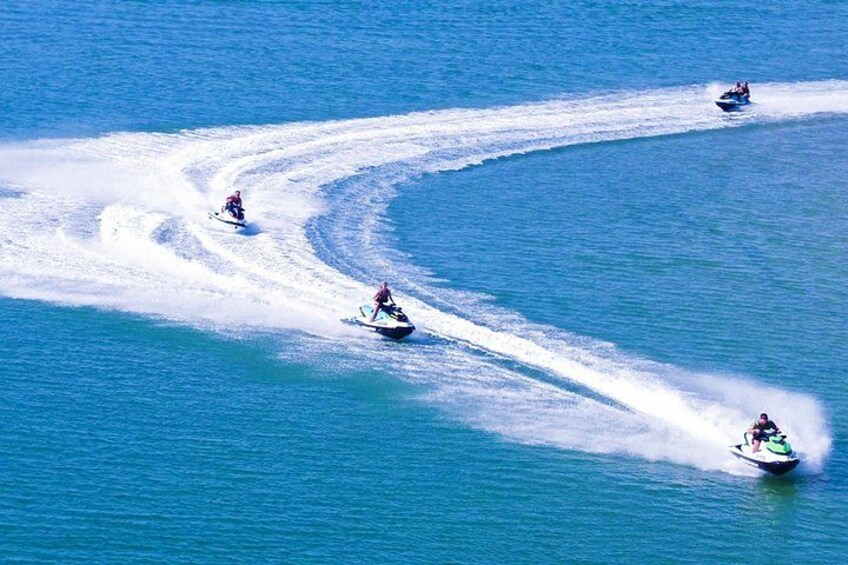 Three jet skis creating wake trails in the ocean. 5