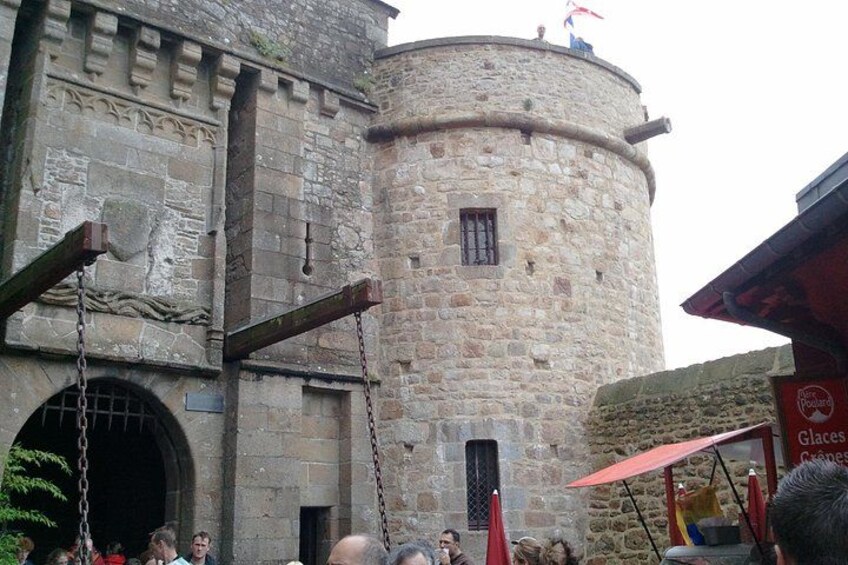 A stone castle with a round tower, a flag on top, and a red umbrella in the foreground. 2