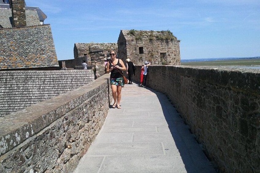 A stone pathway leading to a historic stone building with visitors. 5