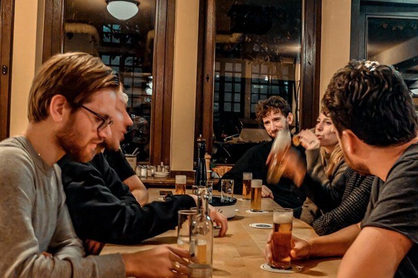 A group of people sitting around a table with drinks, in a room with wooden furniture and large windows. 2