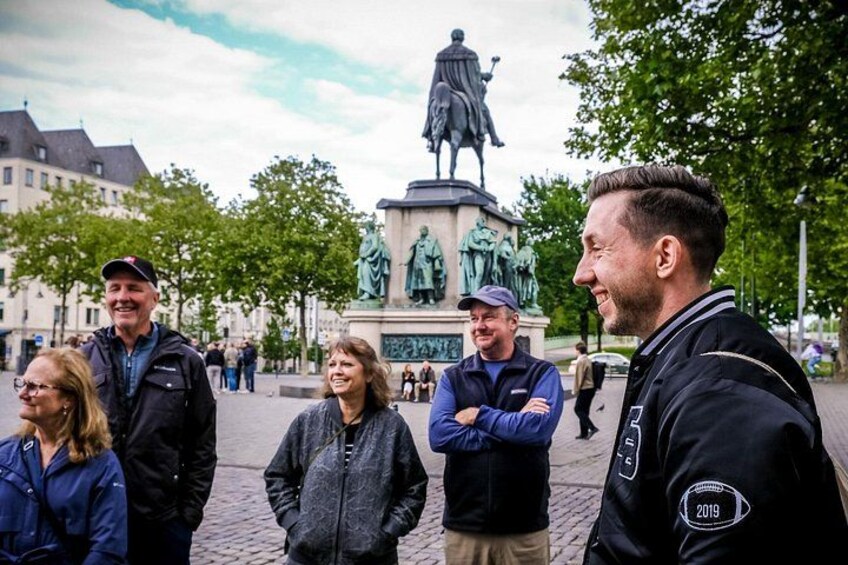 A group of people standing in a public square with a statue in the background. 4