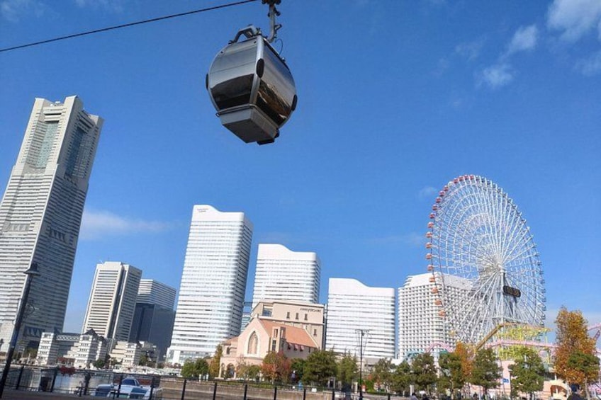 Eine Seilbahn, moderne Wolkenkratzer und ein Riesenrad in einer Stadtansicht. 3
