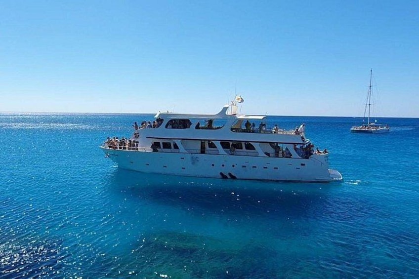 A white boat with passengers on a clear blue sea. 2