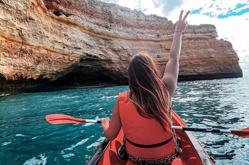 Una persona en kayak sobre un mar turquesa, con un acantilado rocoso al fondo. 3